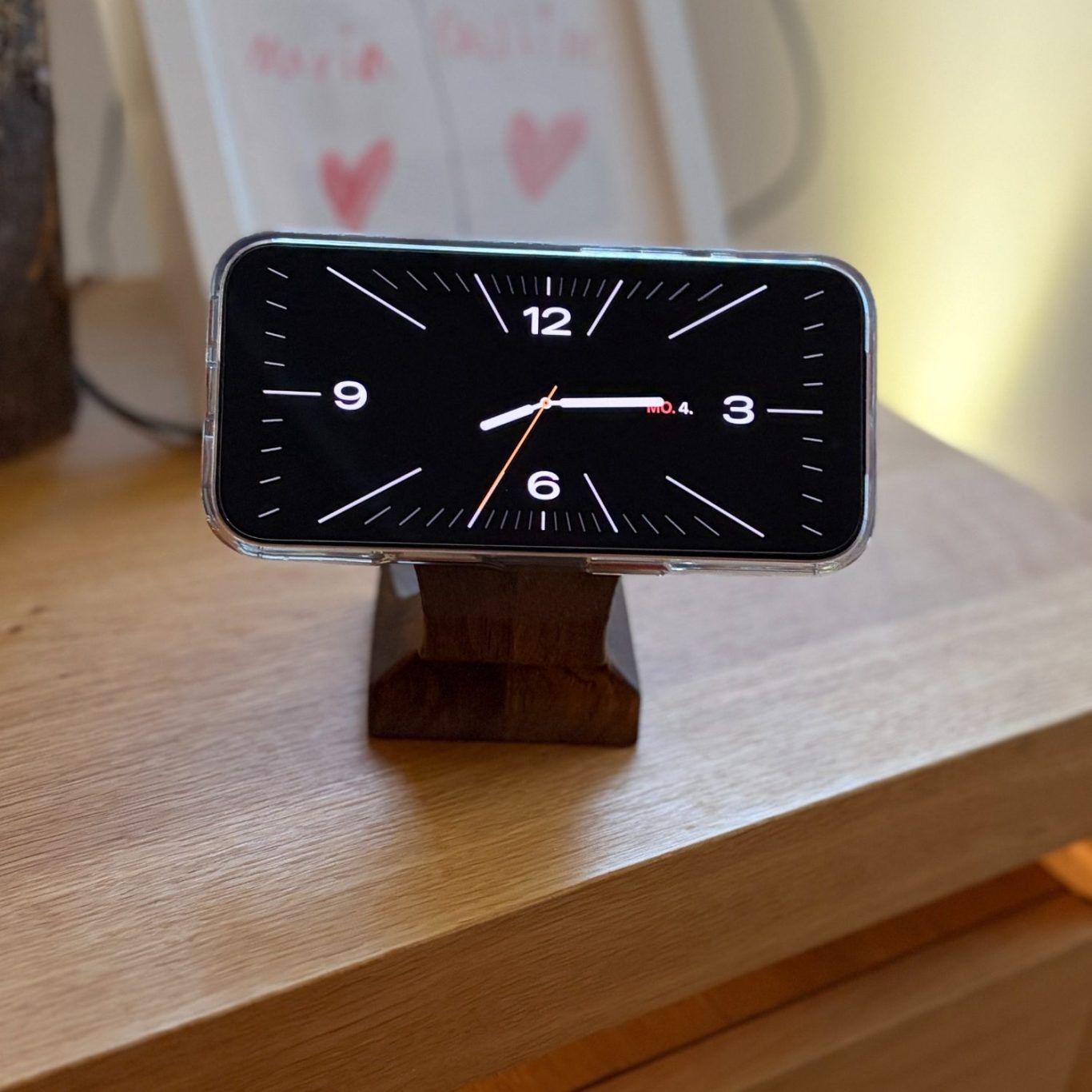 Smartphone Ladestation aus Massivholz IPhone hängt an induktiver Ladestation aus dunklem Eichenholz