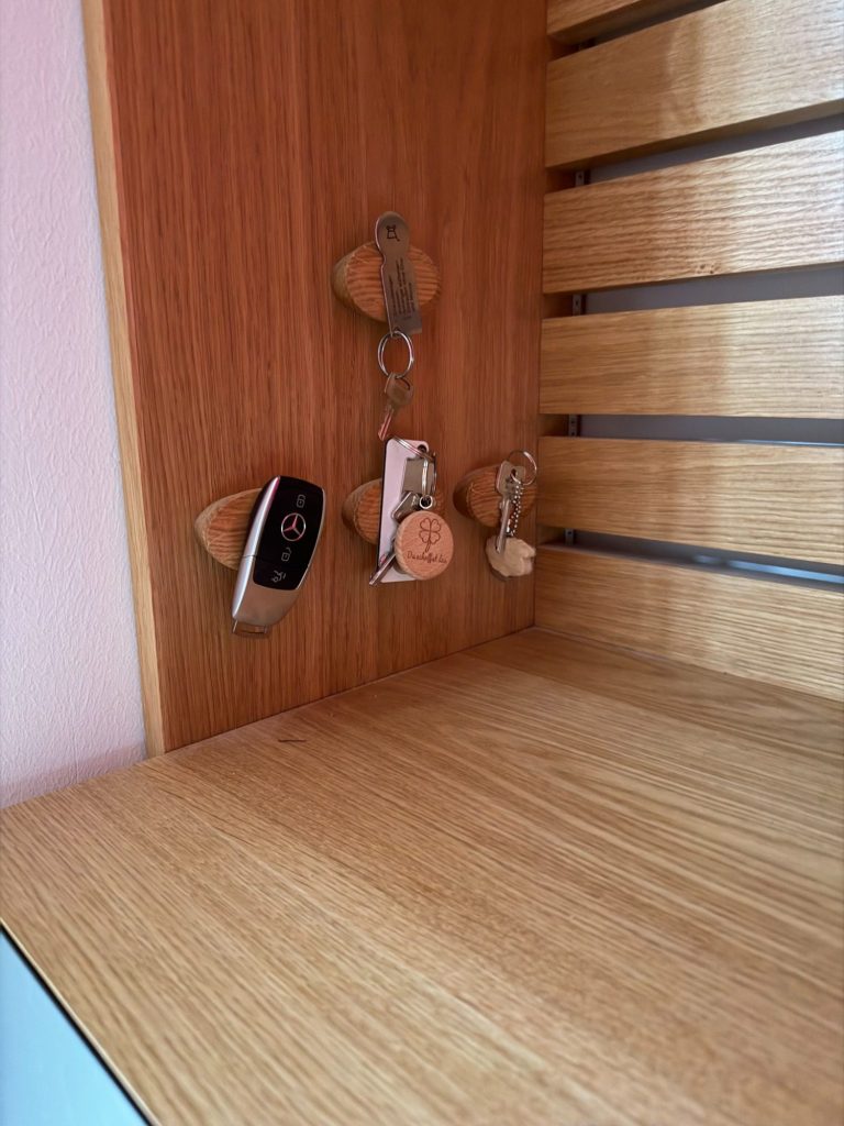 Schlüsselbrett Drei Schlüsselbund mit Schlüsselanhängern an einer Holzleiste.